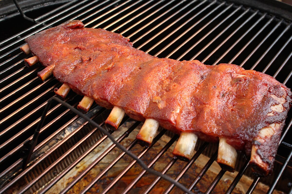 Pork ribs glazed with sauce on a barbecue grill grate