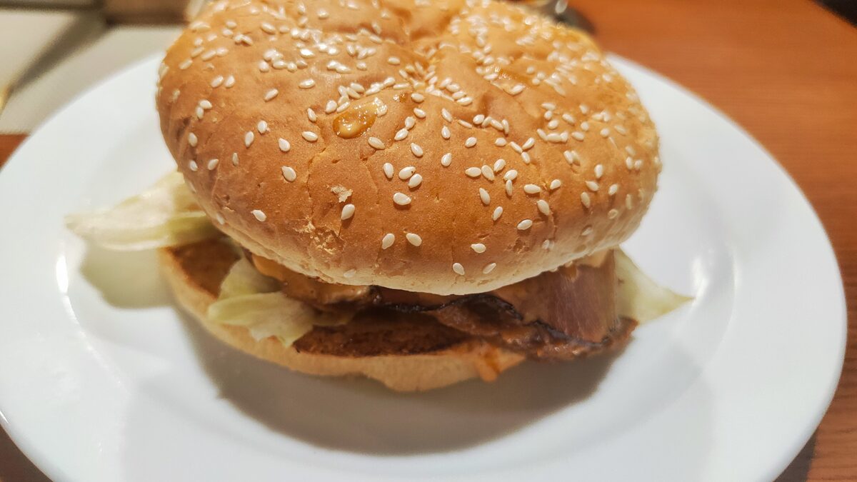 A sesame-seed burger with lettuce on a white plate