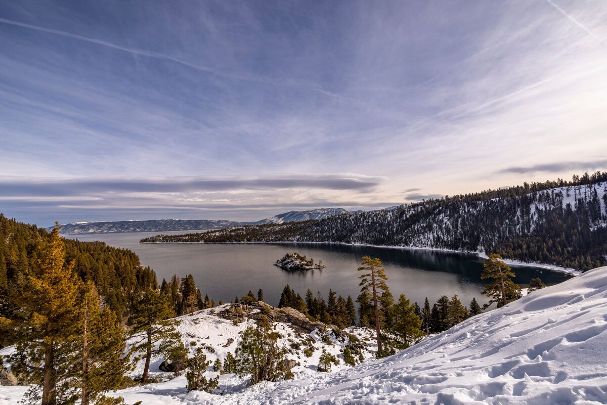 Emerald Bay in winter, with Fannette Island in the water, snow on the shore and pines in the foreground