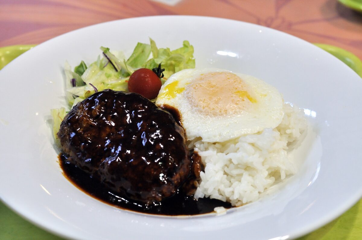 A loco moco plate: rice, a hamburger patty with dark gravy, a fried egg and a small salad