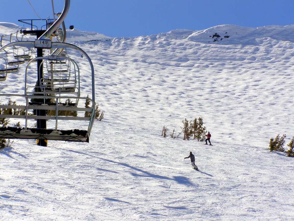 A chairlift above a wide snowy run at Kirkwood, with one skier on the slope below