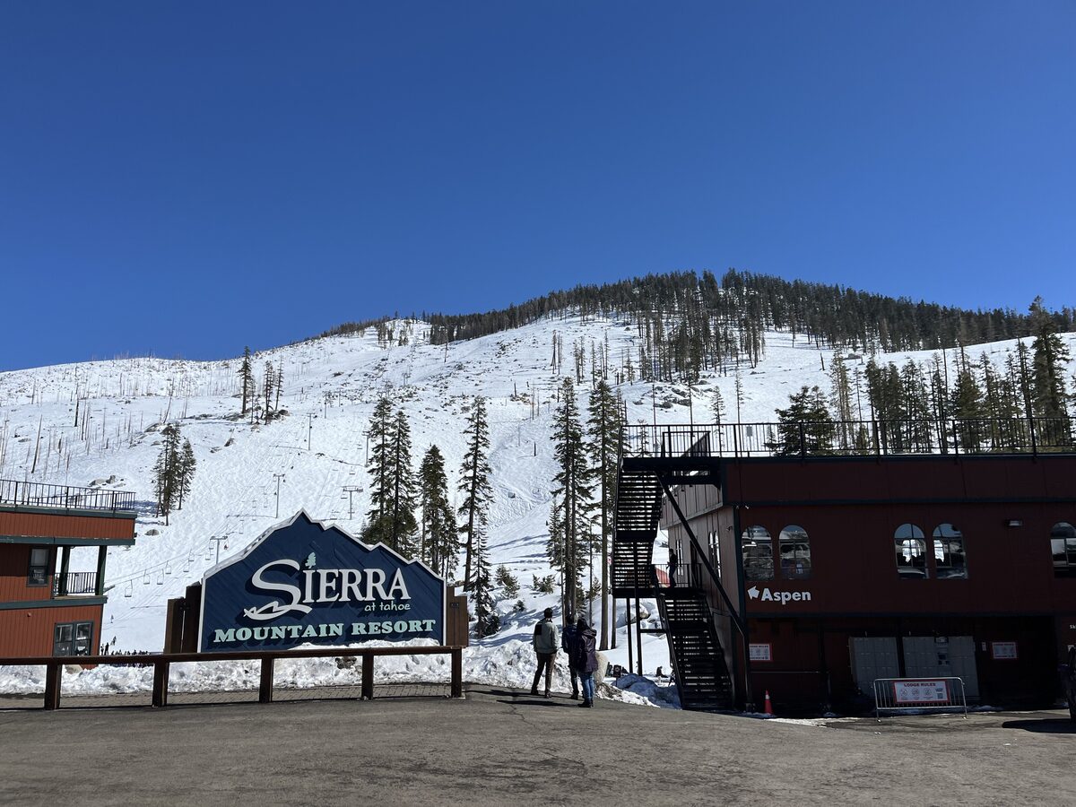 The Sierra Mountain Resort sign and a lodge at the foot of a snowy slope