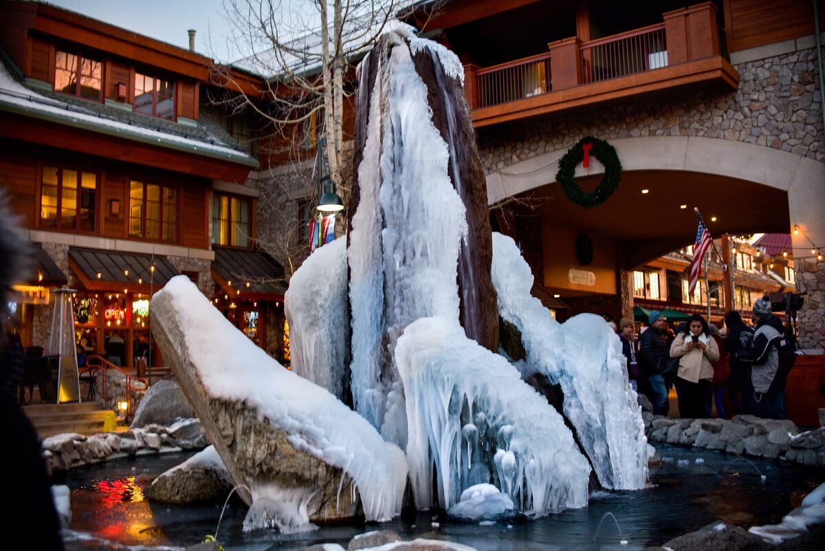 Heavenly Village in winter, with an ice-covered fountain and holiday lights in front of the buildings