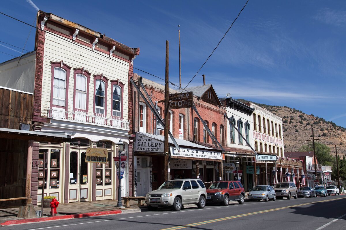 Main Street in Virginia City, with old wooden storefronts and parked cars under a blue sky