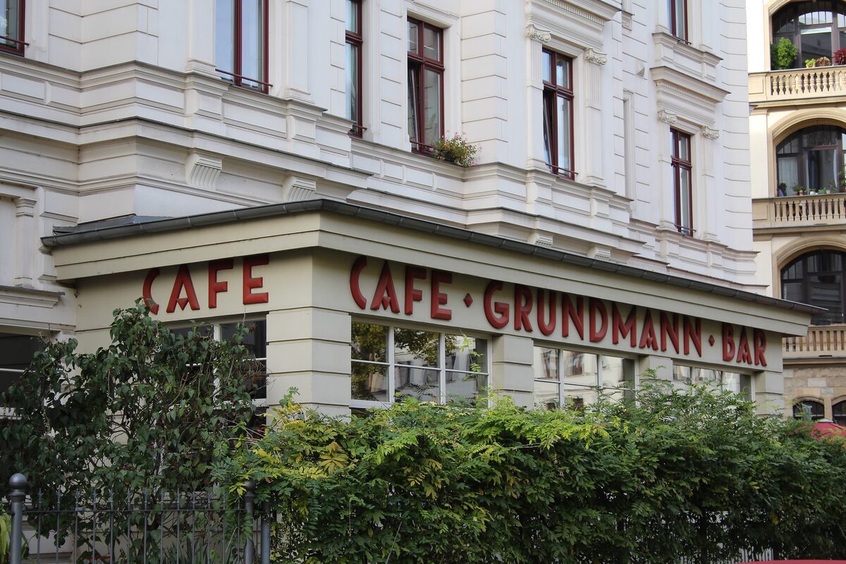 The corner of Café Grundmann with its red lettering above the windows, on a pale 19th-century building