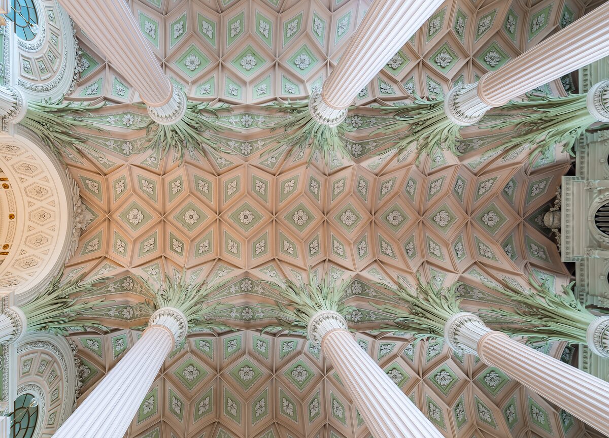The ceiling of the Nikolaikirche seen from below, with white columns ending in green palm-leaf capitals