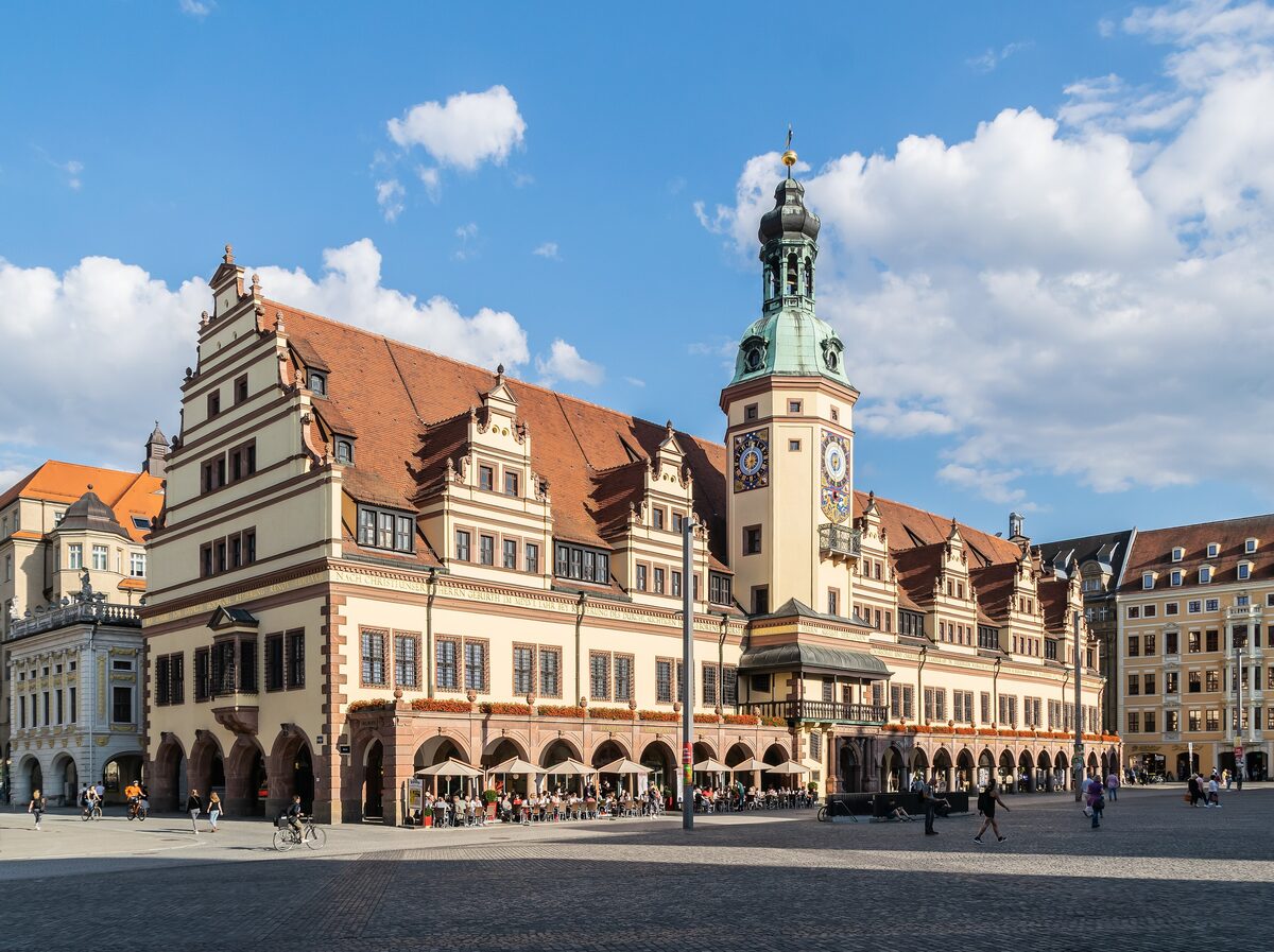 The Old Town Hall on Leipzig's market square, with its arcades, Renaissance gables and green-roofed clock tower under a blue sky