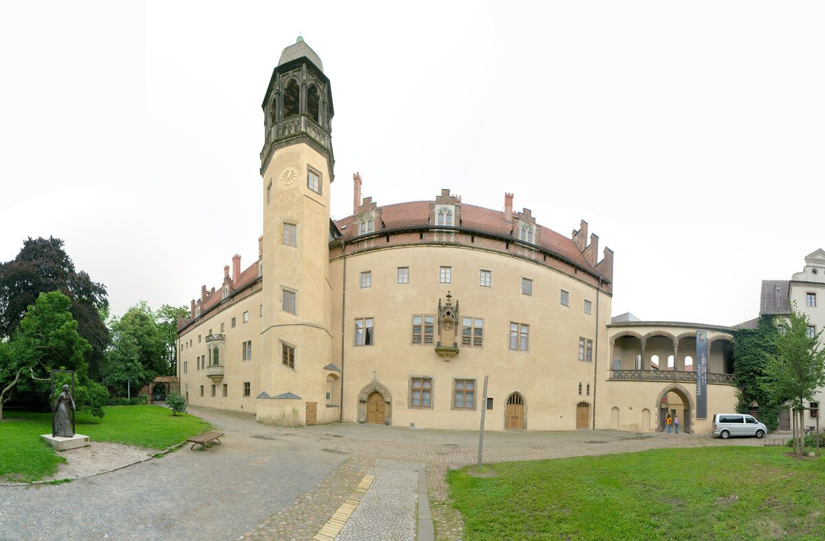 The Lutherhaus in Wittenberg, a large pale former monastery with a tall tower, seen from its courtyard