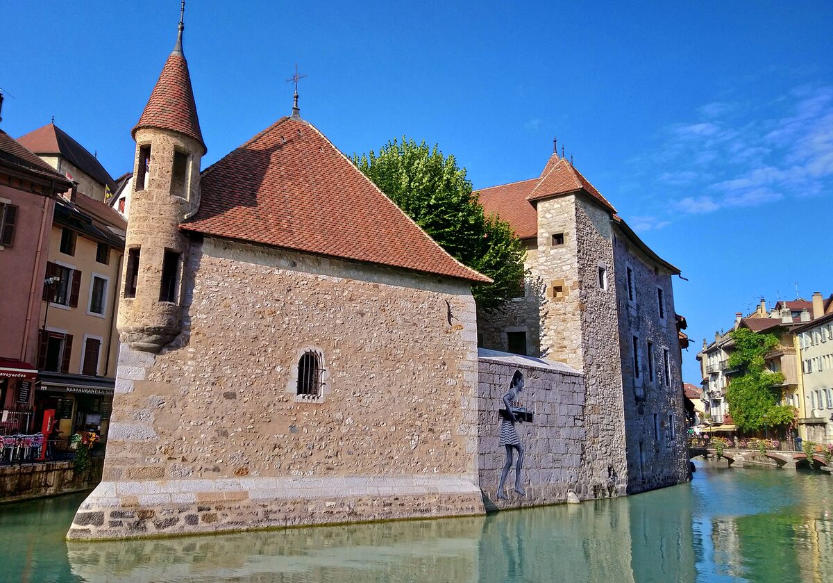 The stone Palais de l'Isle in the canal of Annecy's old town under a bright blue sky