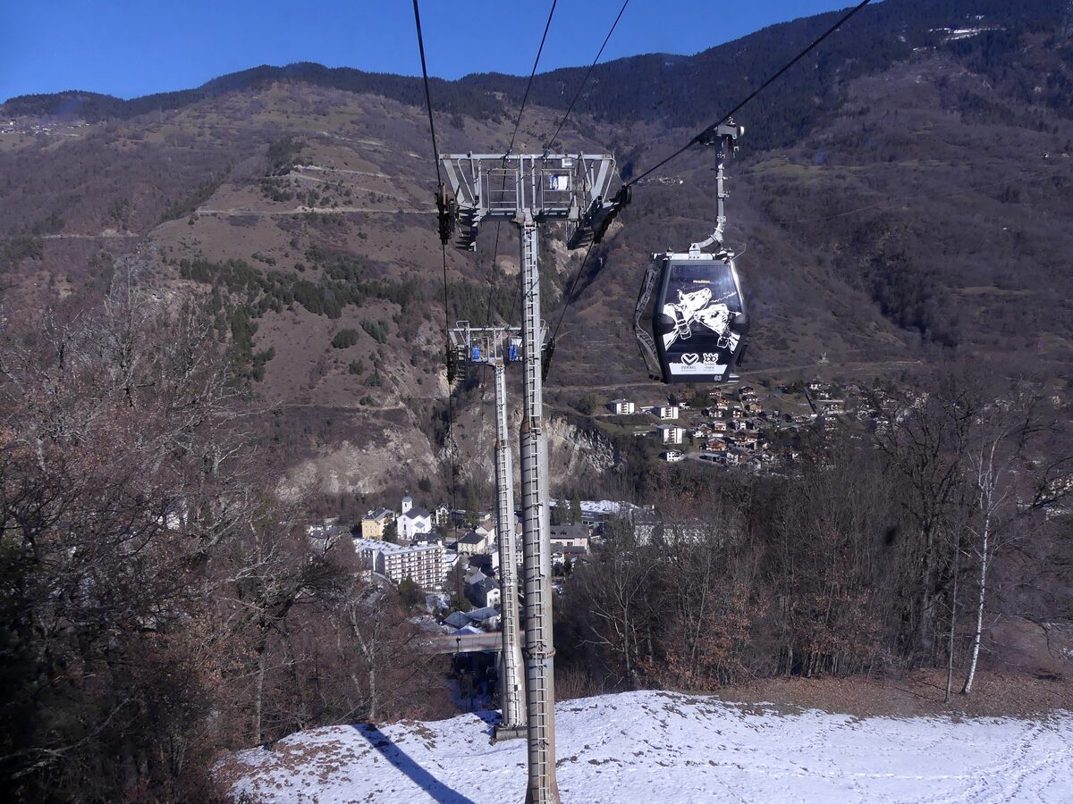 Olympe gondola cabins over the trees above Brides-les-Bains, with snow on the slopes