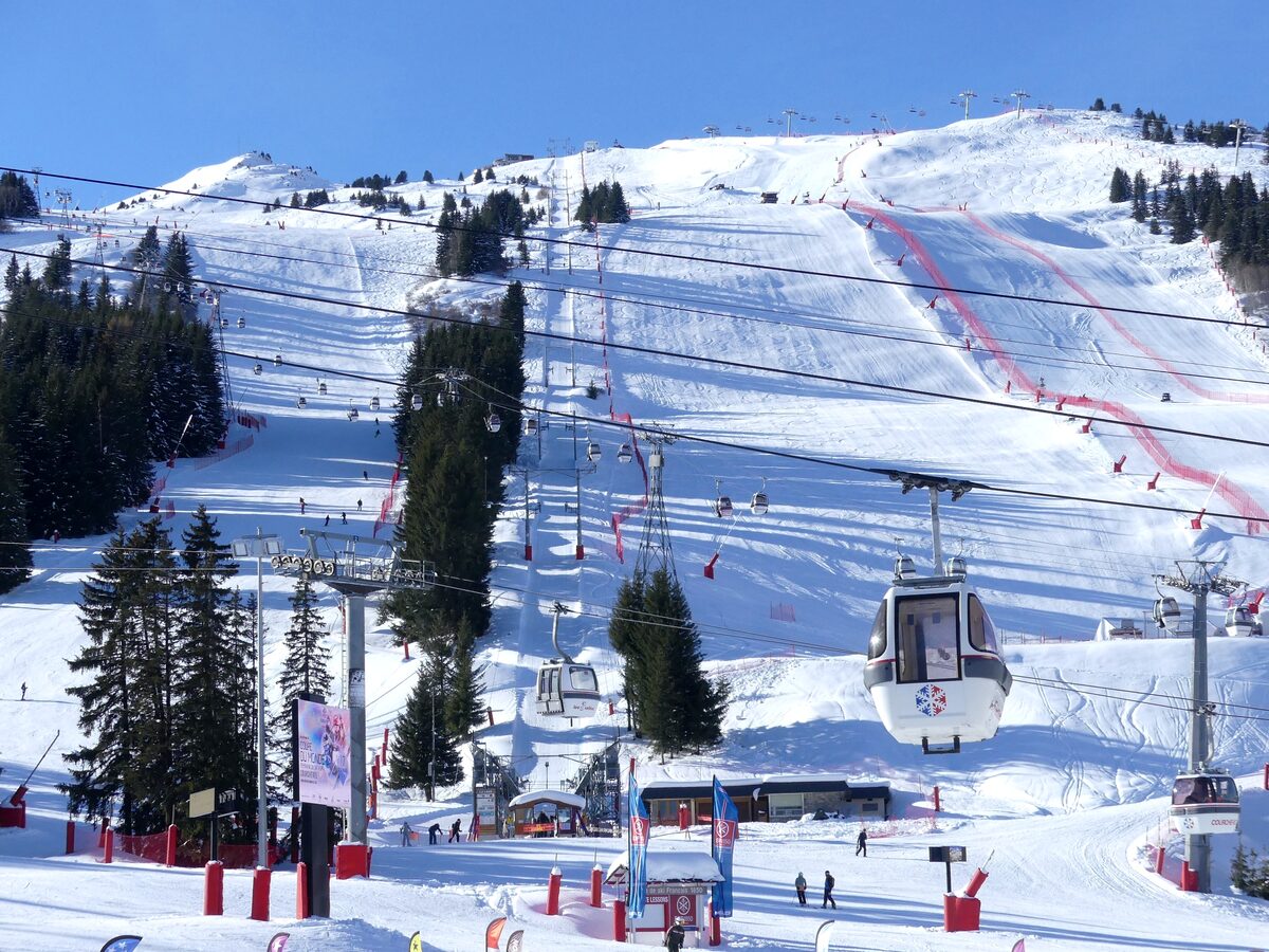 Groomed pistes on the Loze side above Courchevel 1850 with a gondola in front and a red-netted race run
