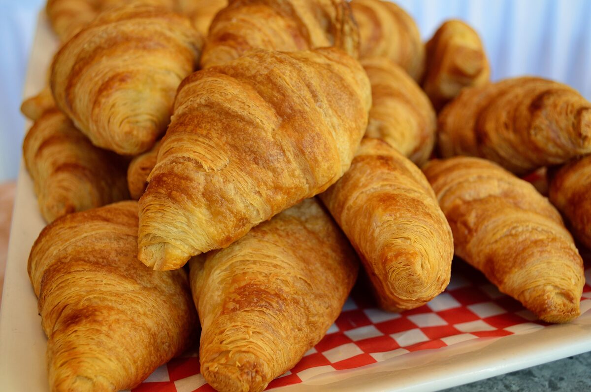 A pile of golden, flaky croissants on a tray