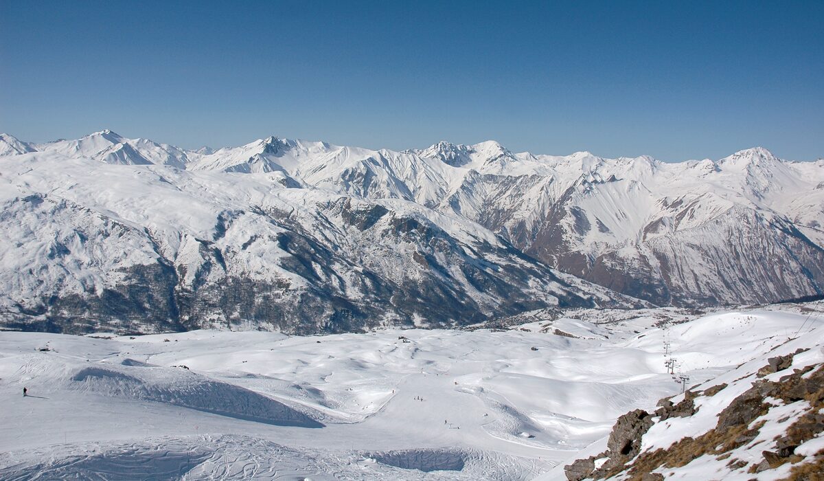 A snow-covered plateau and a wide range of snowy peaks seen from the Tougnète on a clear day