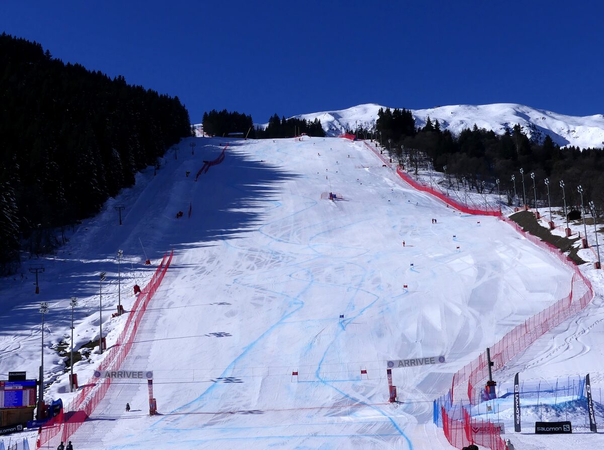 The wide, steep Roc de Fer run in Méribel with its red race netting and finish area under a deep blue sky