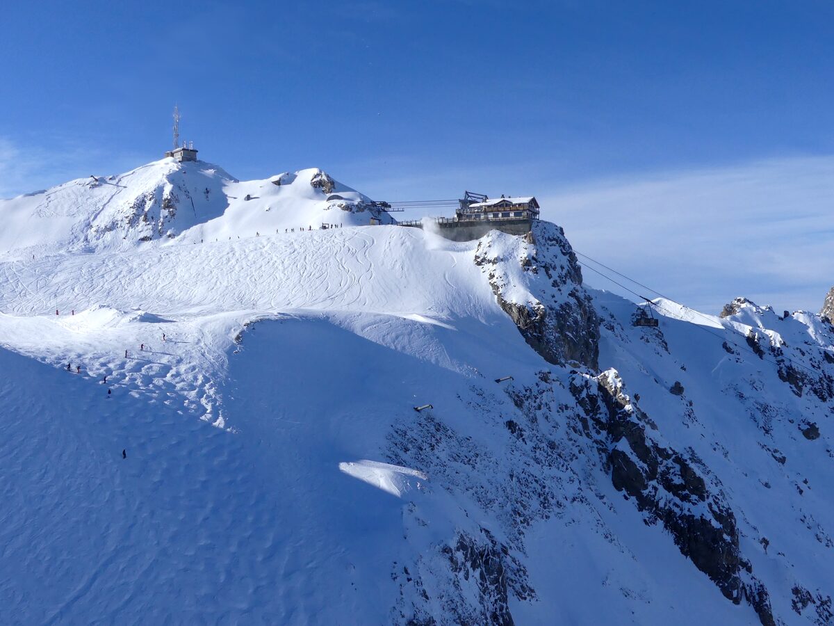 The snowy Saulire summit with its station on the ridge under a clear blue sky