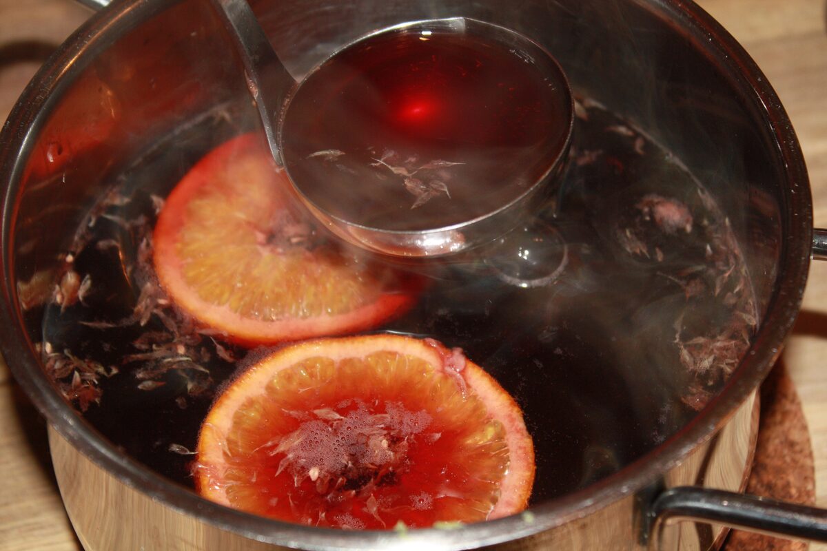 A pot of mulled red wine with orange slices and a ladle, the drink behind every vin chaud