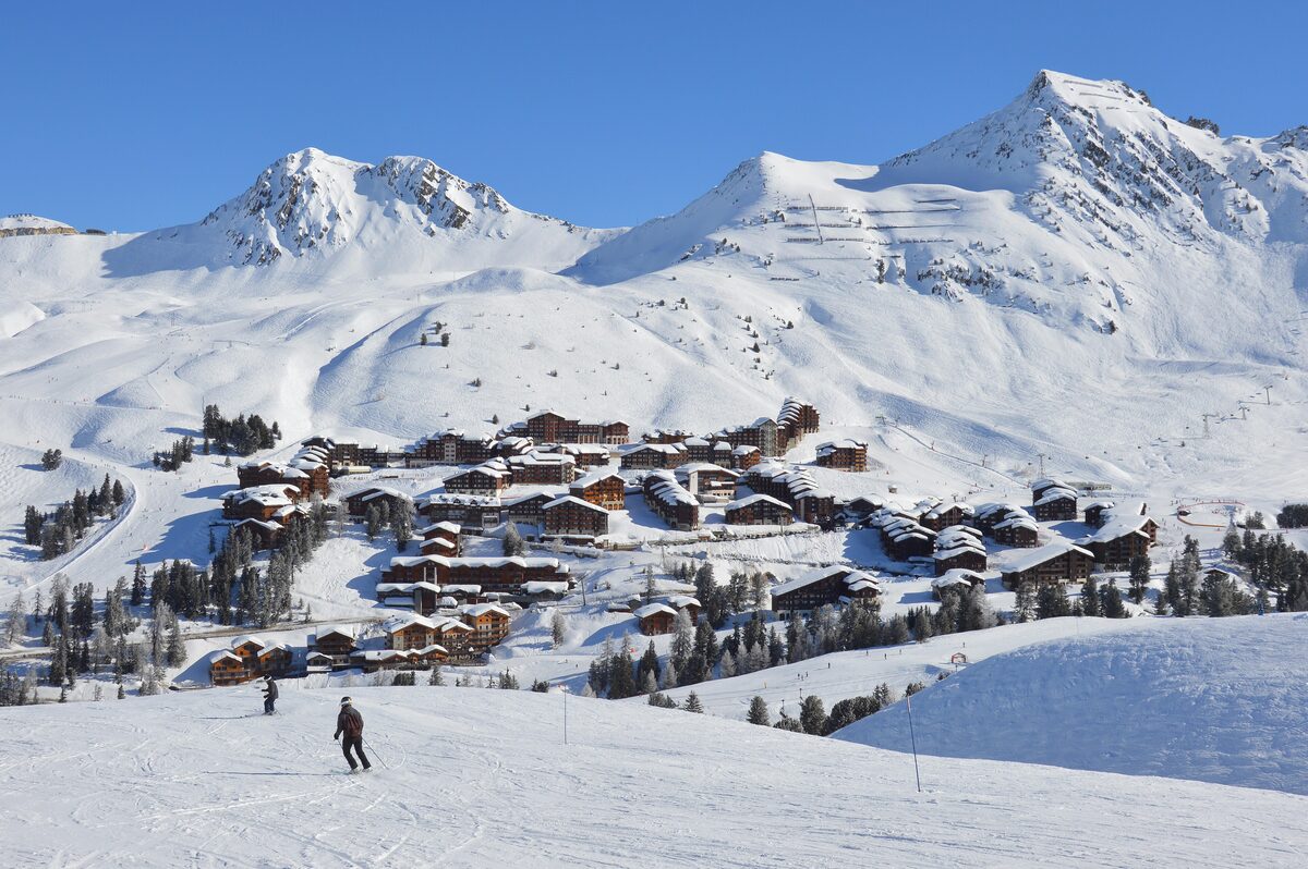 Belle Plagne's chalets and a skier on the snowy slopes below the Plagne peaks