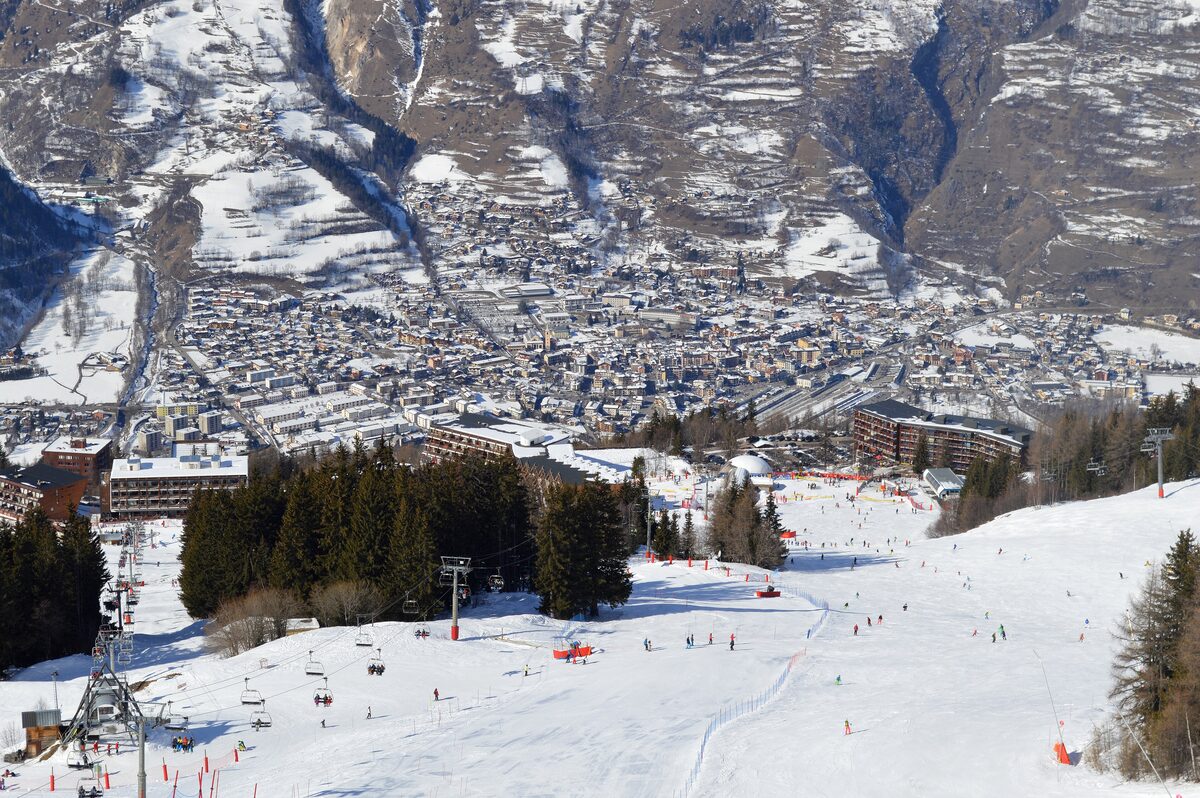Bourg-Saint-Maurice's rooftops in the valley below snowy slopes, seen from the Arc 1600 pistes