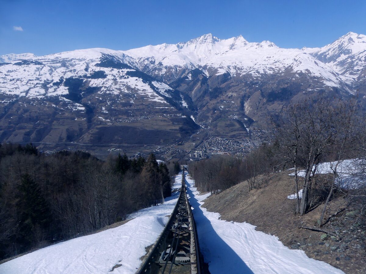 The funicular track running down through snow from Arc 1600 toward Bourg-Saint-Maurice, with snowy peaks across the valley