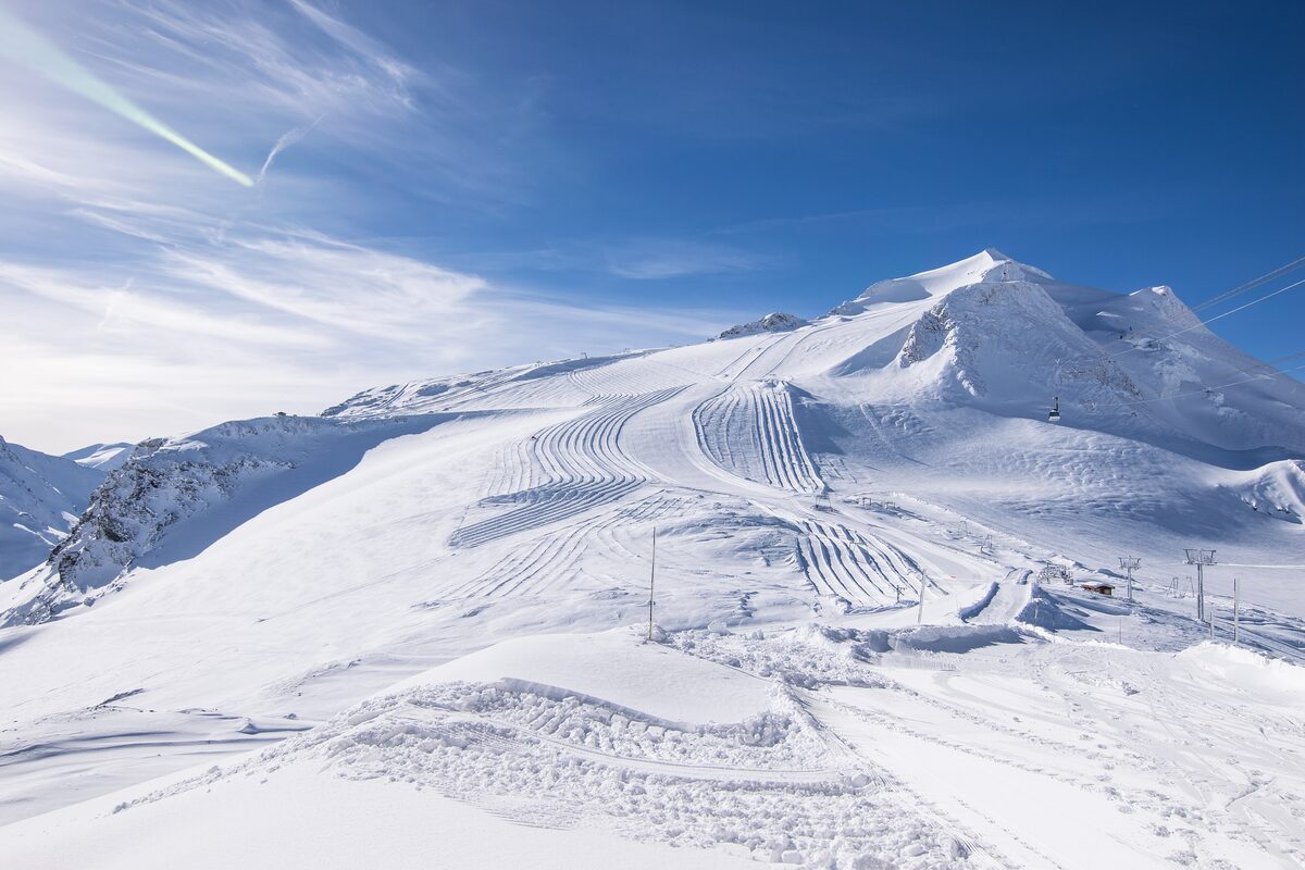 Groomed snow on the Grande Motte glacier above Tignes under a blue sky