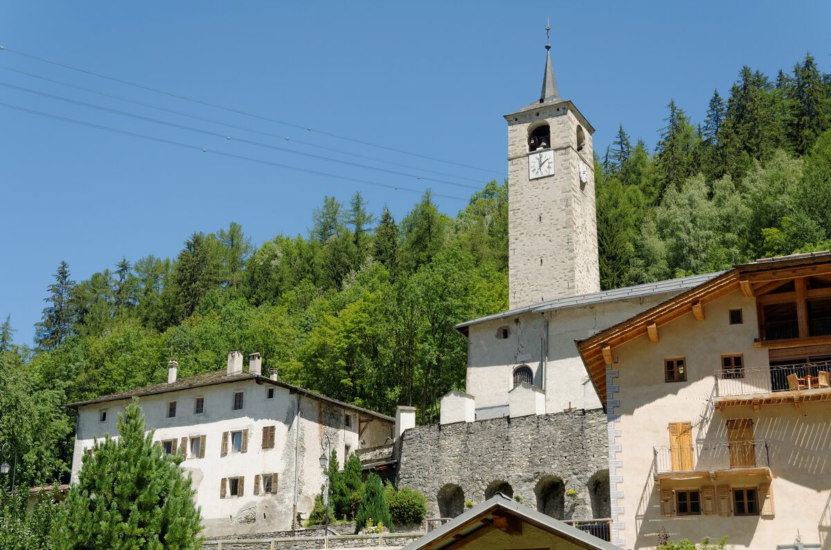 The slim bell tower of the Trinité church above the stone houses of Peisey-Nancroix, in summer