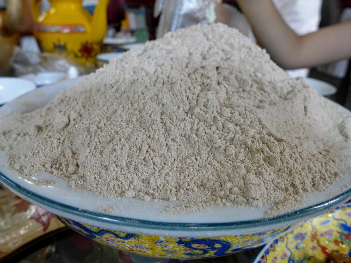 A large mound of roasted barley flour in a dragon-painted bowl on a restaurant table