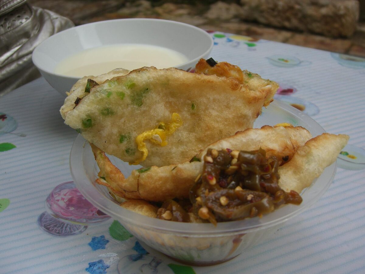 Pan-fried Lijiang baba flatbread with spring onion and chili sauce, with a bowl behind