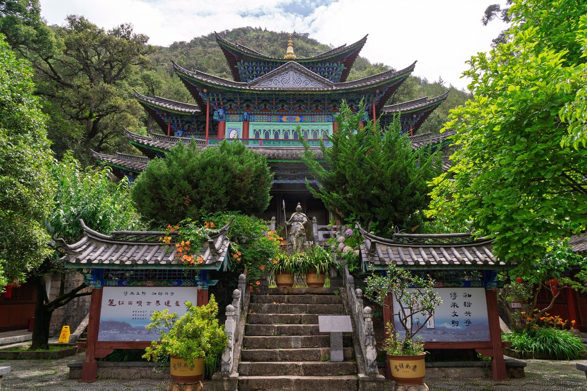 The Five Phoenix Hall at Black Dragon Pool, a multi-roofed hall with painted eaves seen up a short stone stair between flowering pots and trees