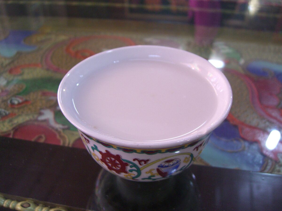 A decorated cup of creamy butter tea on a brightly patterned table