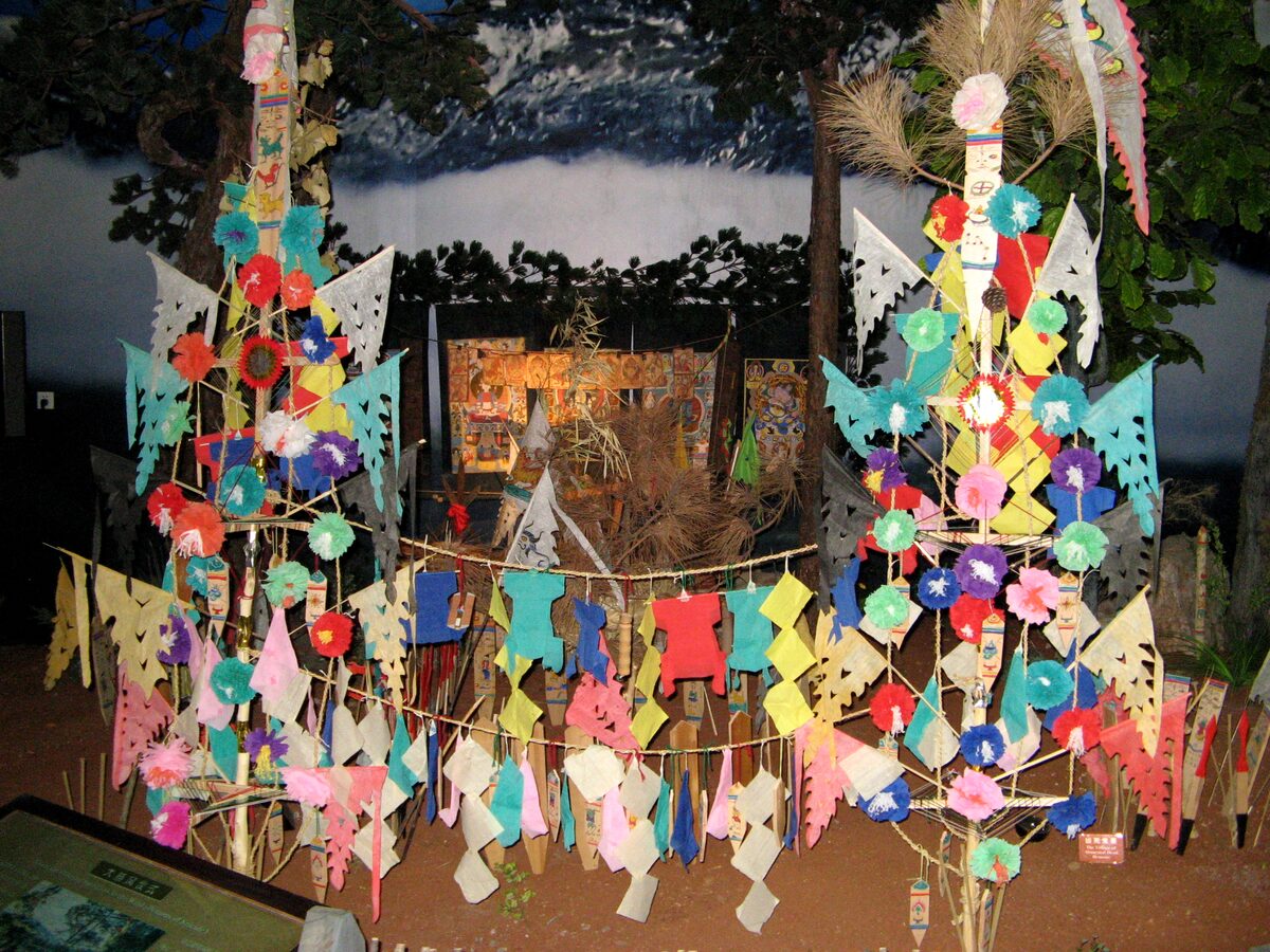 Colorful paper-cut ritual banners on a tall ornamental frame in a Dongba culture exhibit