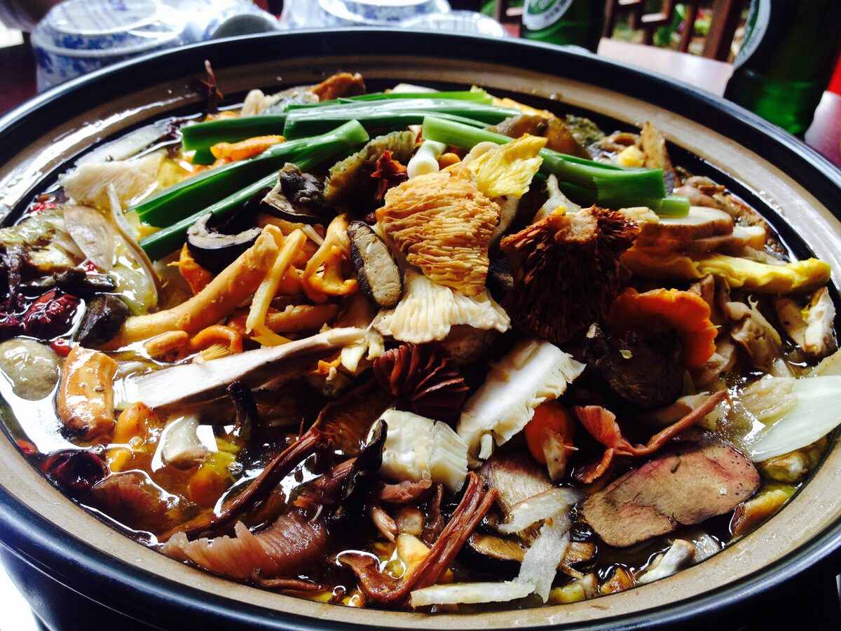 A Yunnan wild mushroom hot pot piled with mixed mushrooms and green vegetables