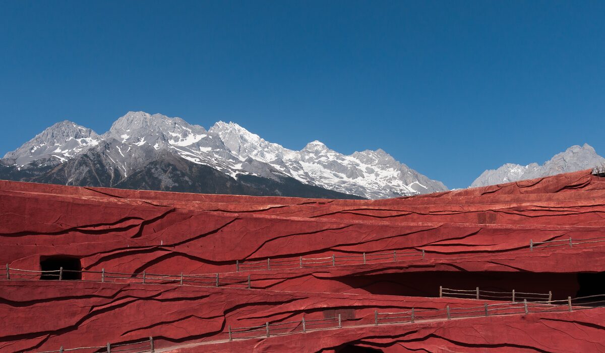 The red terraced stage of the Impression Lijiang open-air theater, with the snowy ridge of Jade Dragon Snow Mountain above it