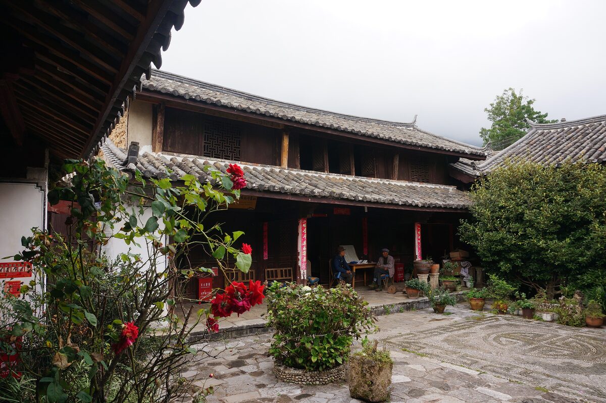 A courtyard house with tiled eaves and red flowers, the former residence of Joseph Rock in Yuhu village