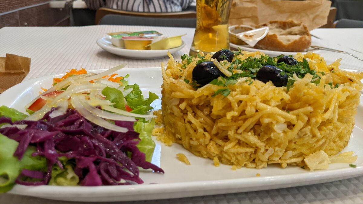 Bacalhau à Brás, shredded salt cod with straw potatoes and olives, served with a salad