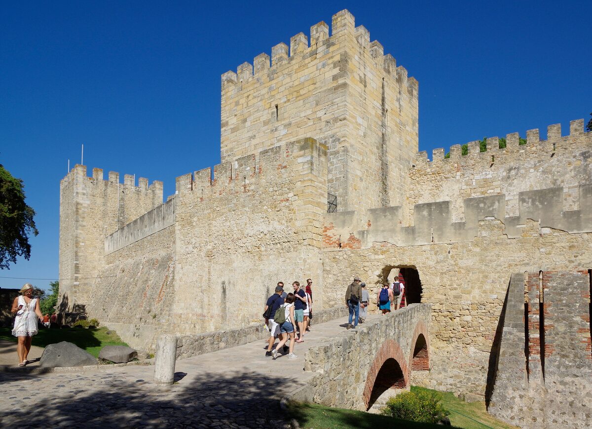 The keep and walls of São Jorge Castle, with visitors crossing the approach