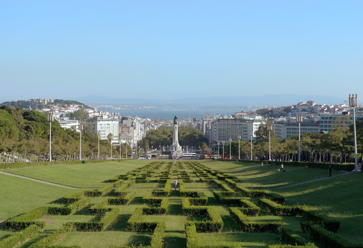 The clipped hedge parterres of Parque Eduardo VII running downhill toward the Marquês de Pombal column and the river