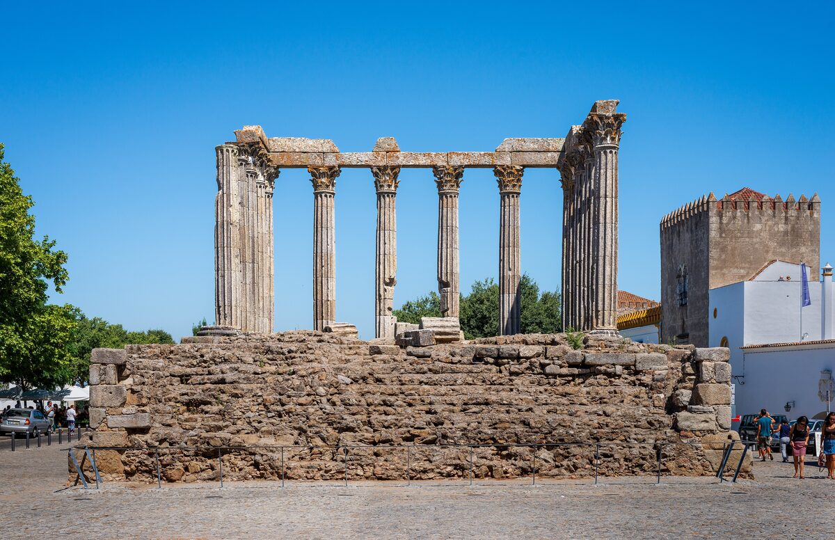 Columns of the Roman Temple of Évora on their granite podium, with a medieval tower beside it