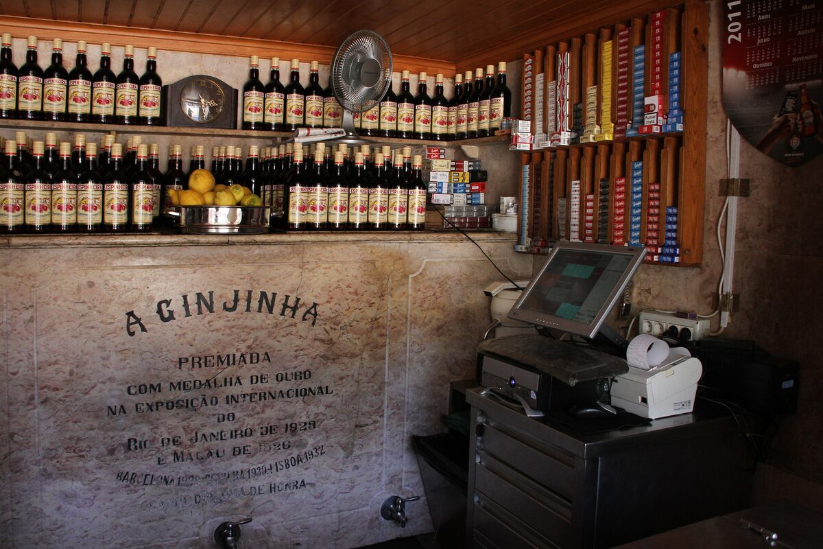 Bottles of ginjinha lined up on shelves behind the counter at A Ginjinha