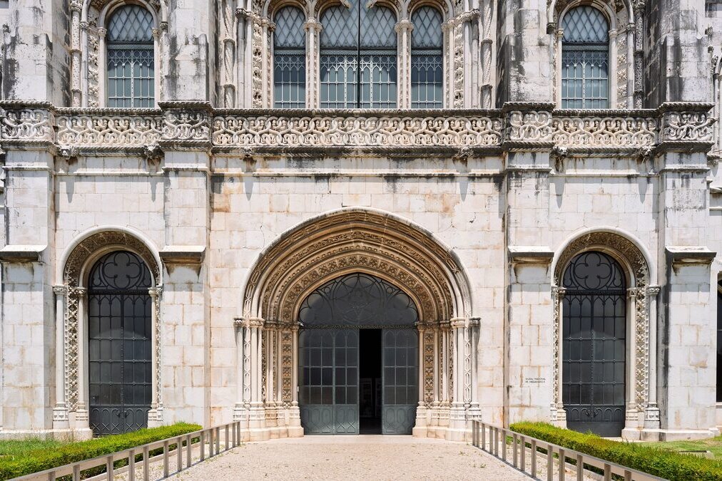 The carved entrance of the Jerónimos Monastery, with a pointed doorway and tall windows on either side
