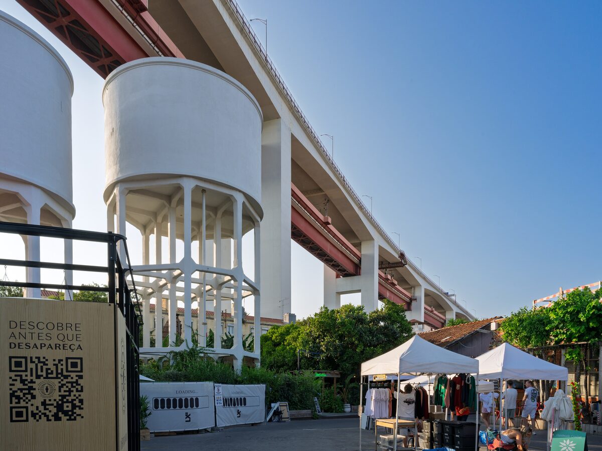 White water towers and market stalls beneath the 25 de Abril Bridge at LX Factory