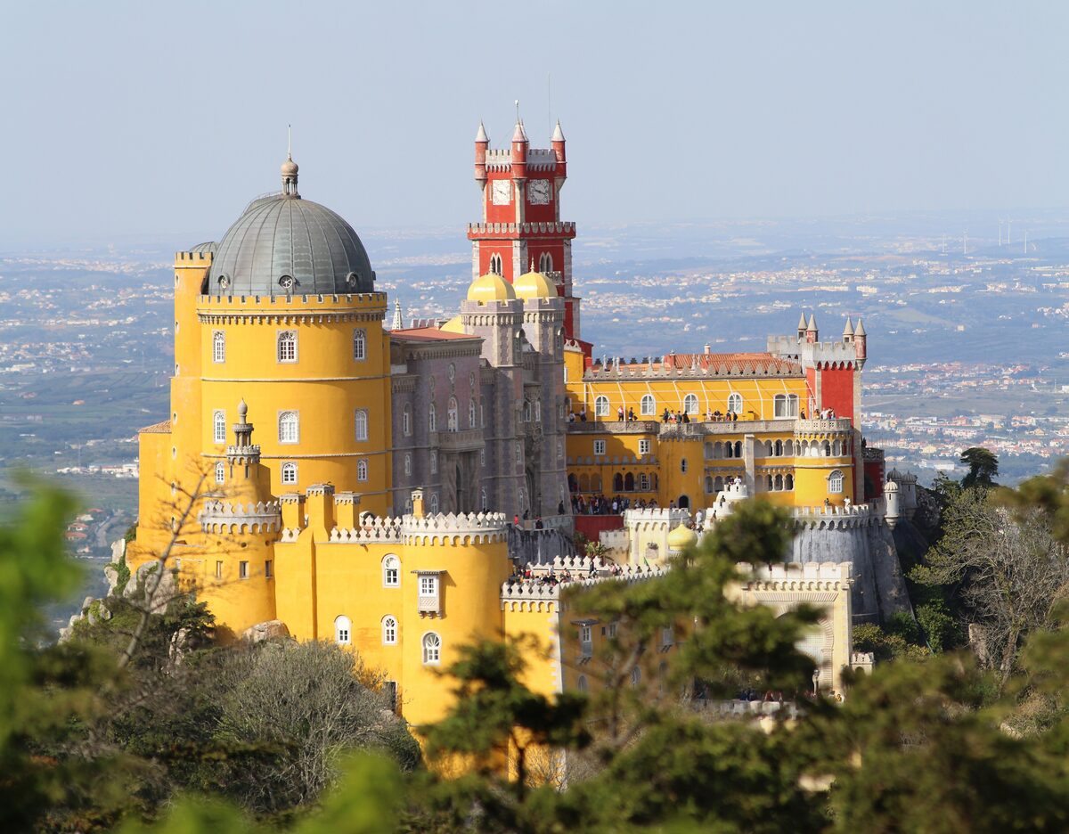 The yellow and red Pena Palace on its hilltop above Sintra, with the plain of Lisbon far below