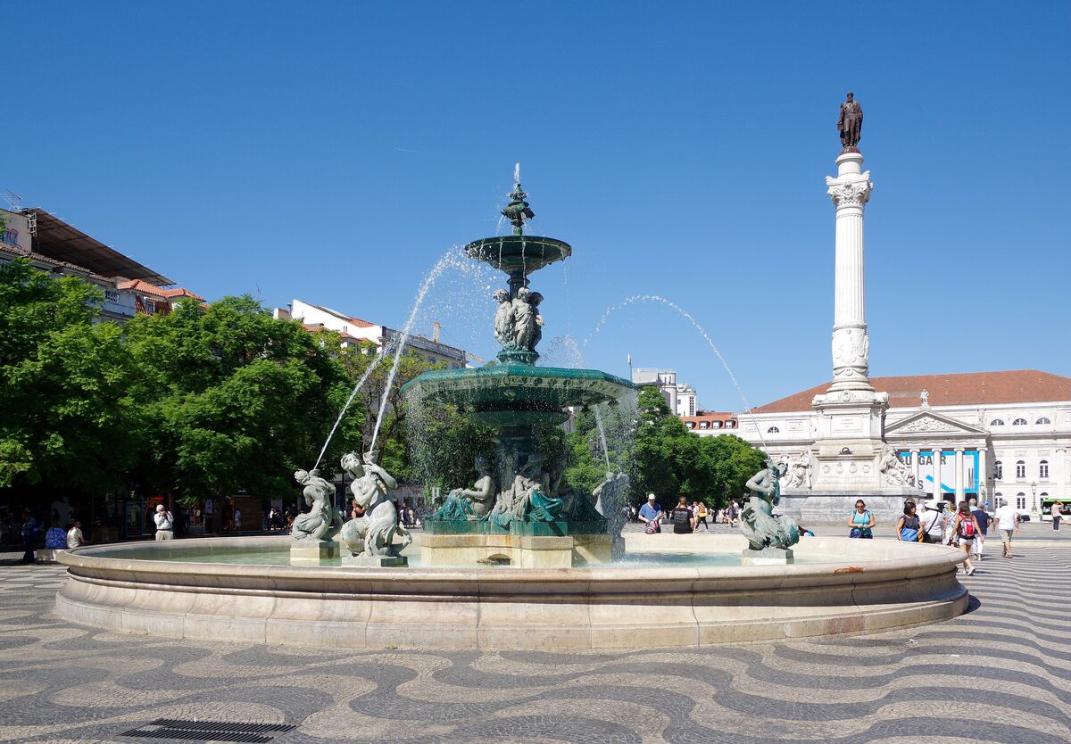 The bronze fountain and the column of Pedro IV on Rossio square, with its wave-pattern pavement and the National Theatre behind