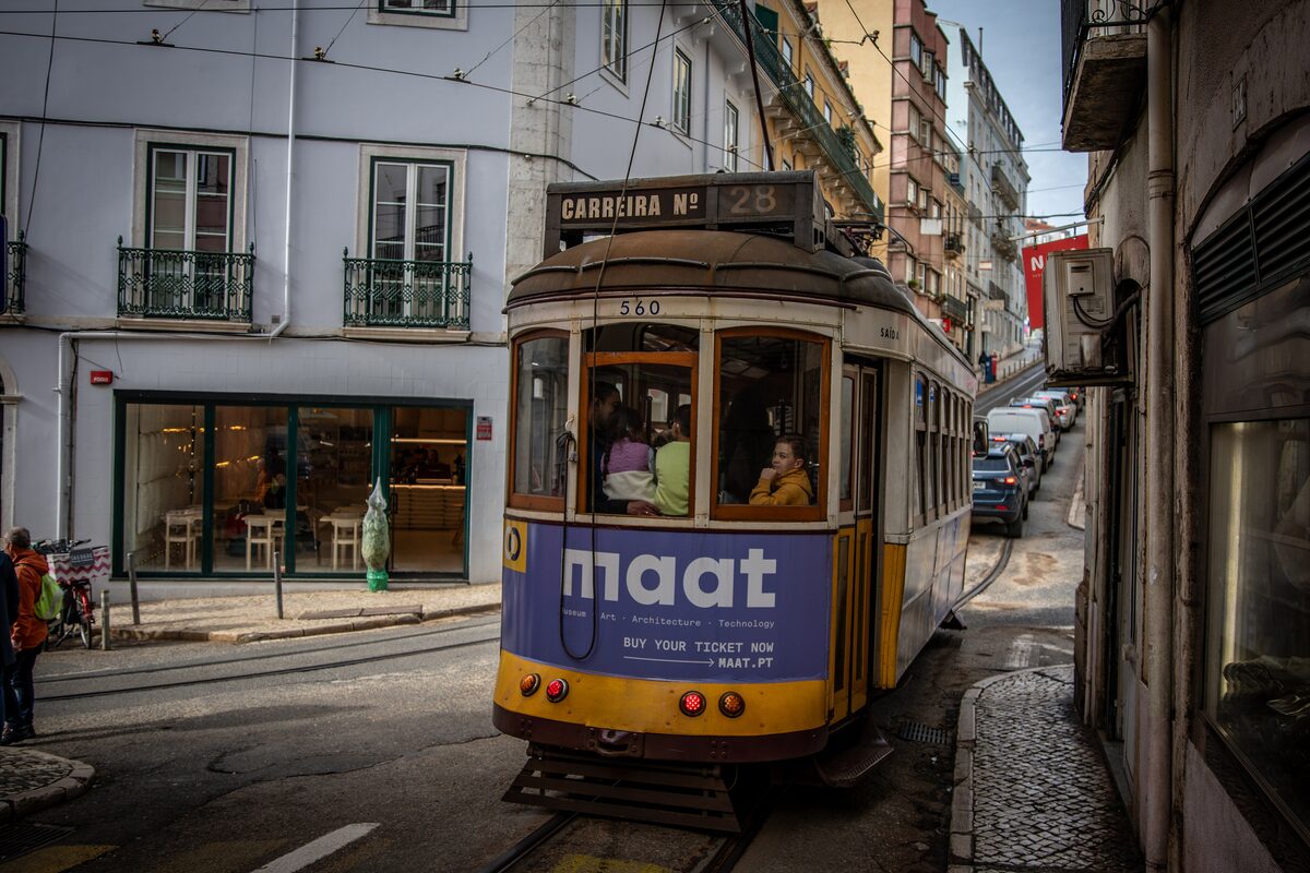 Yellow tram 28 climbing a narrow street, its sign reading Carreira nº 28