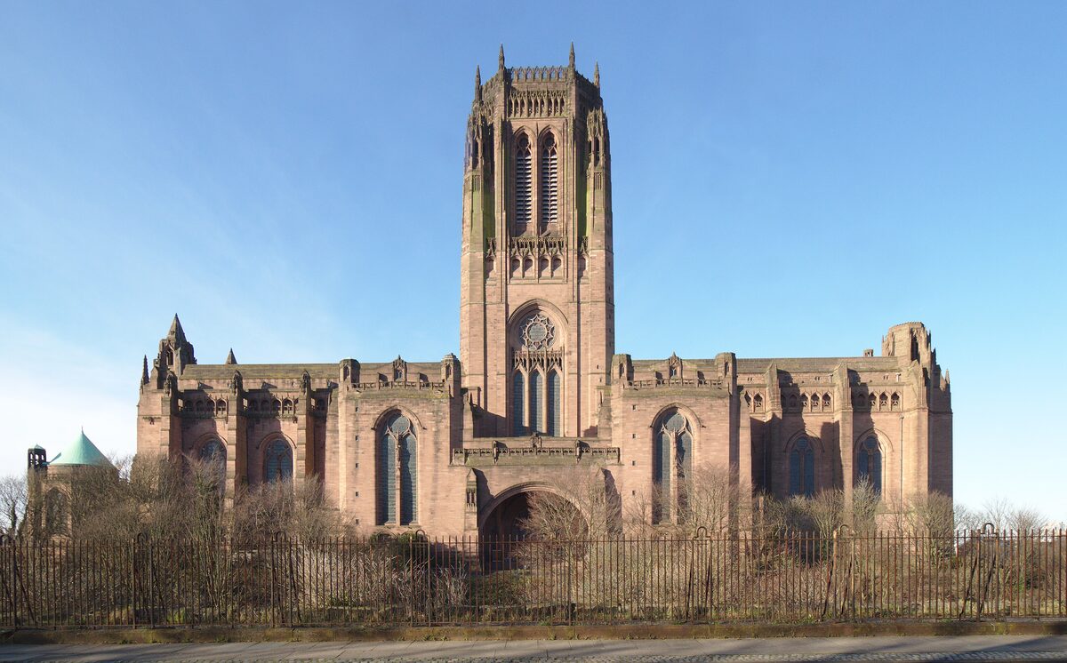 The huge red sandstone Liverpool Cathedral with its massive central tower, seen from a street below