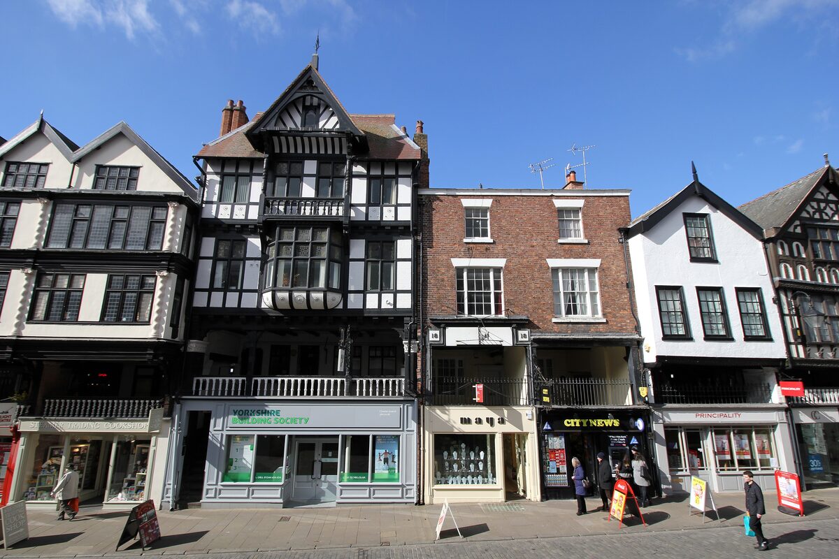 Black-and-white timber-framed buildings on a street in Chester, with a covered gallery of shops on the first floor