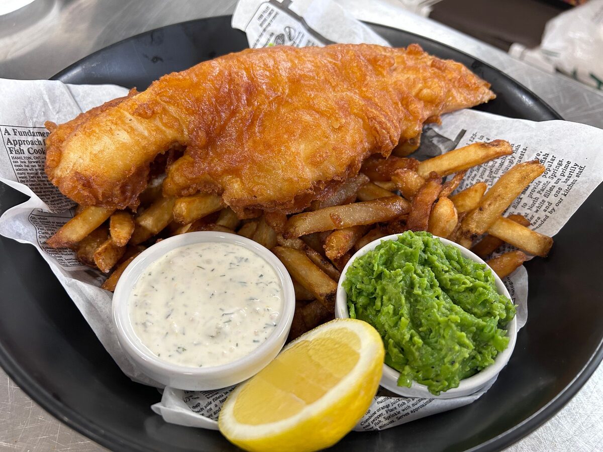 Battered fish and thick chips with a wedge of lemon and mushy peas
