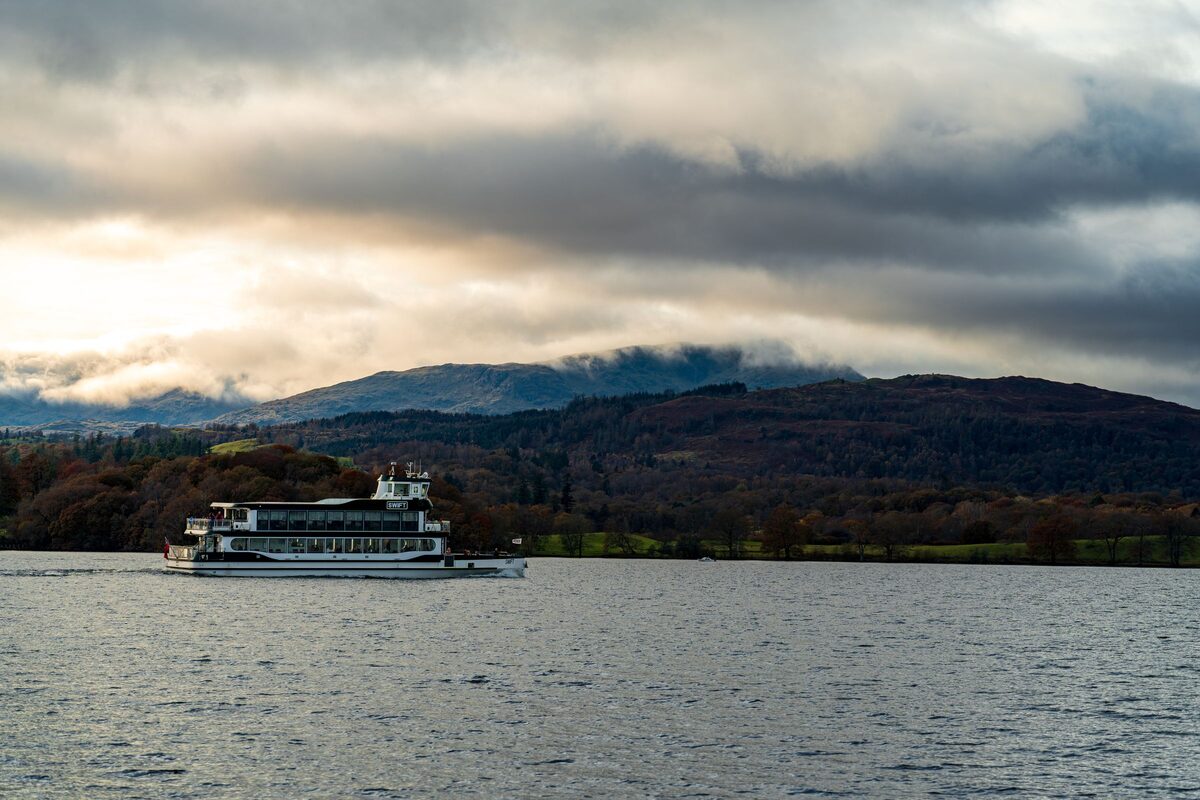 A passenger boat on Windermere, with wooded hills and clouds behind