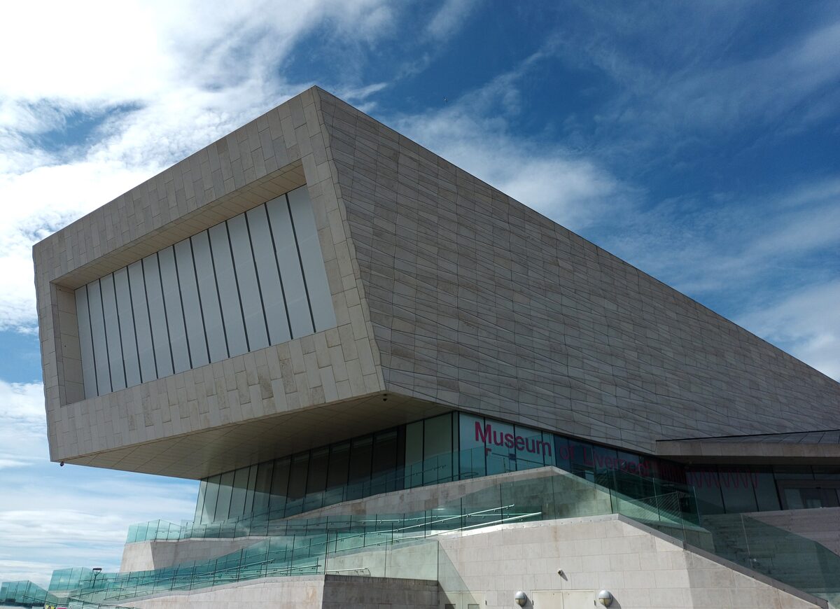 The modern white Museum of Liverpool with its large windows on the waterfront, with the Three Graces behind