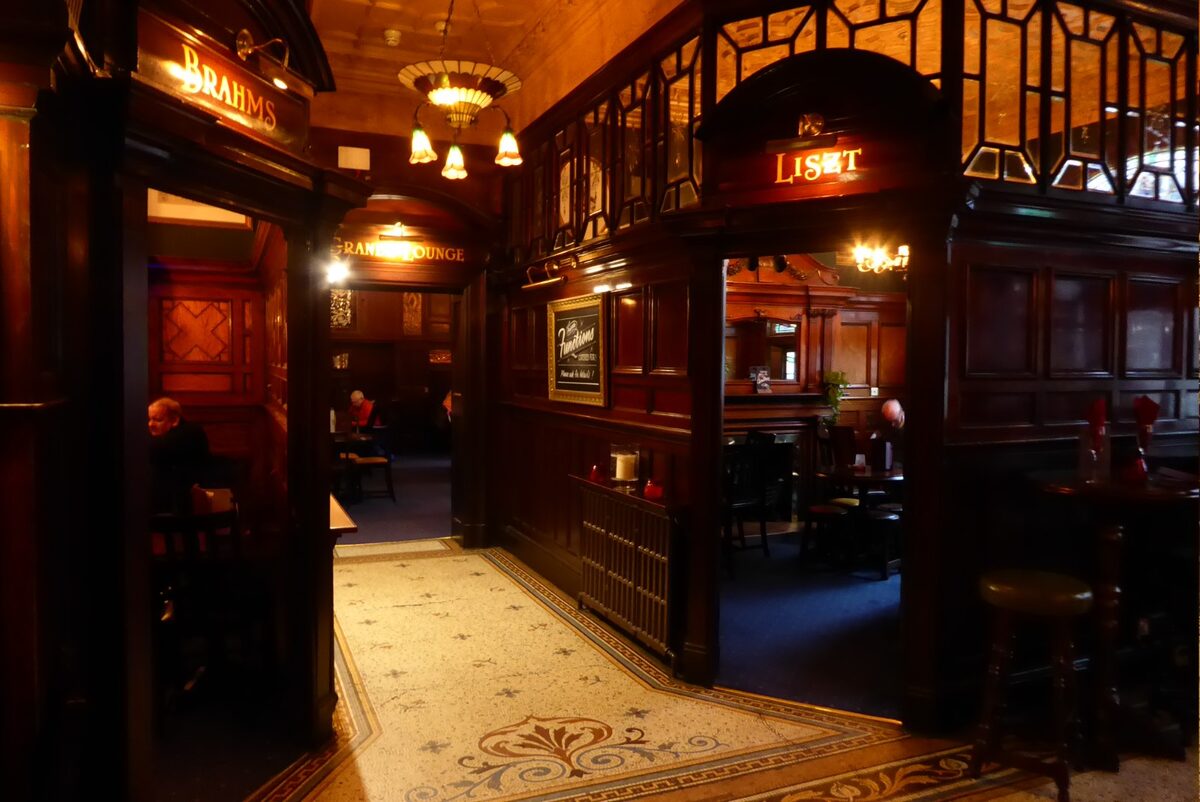 The ornate Victorian interior of the Philharmonic Dining Rooms in Liverpool, with carved wood, stained glass and a mosaic bar