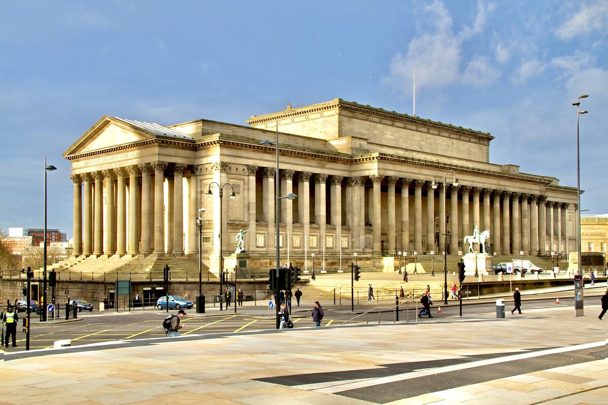 The long neoclassical front of St George's Hall in Liverpool with its rows of tall columns, under a blue sky